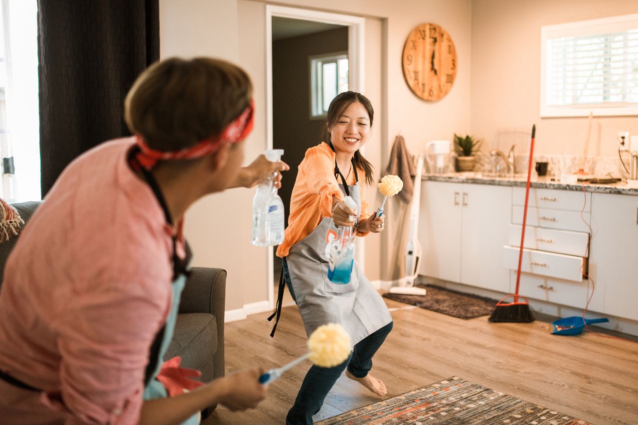 hero-img-02 Asian couple having fun while cleaning their home, enhancing a cheerful atmosphere.